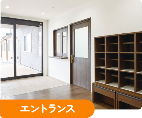 エントランス：ガラス扉の入口と木製の靴箱が並ぶ玄関